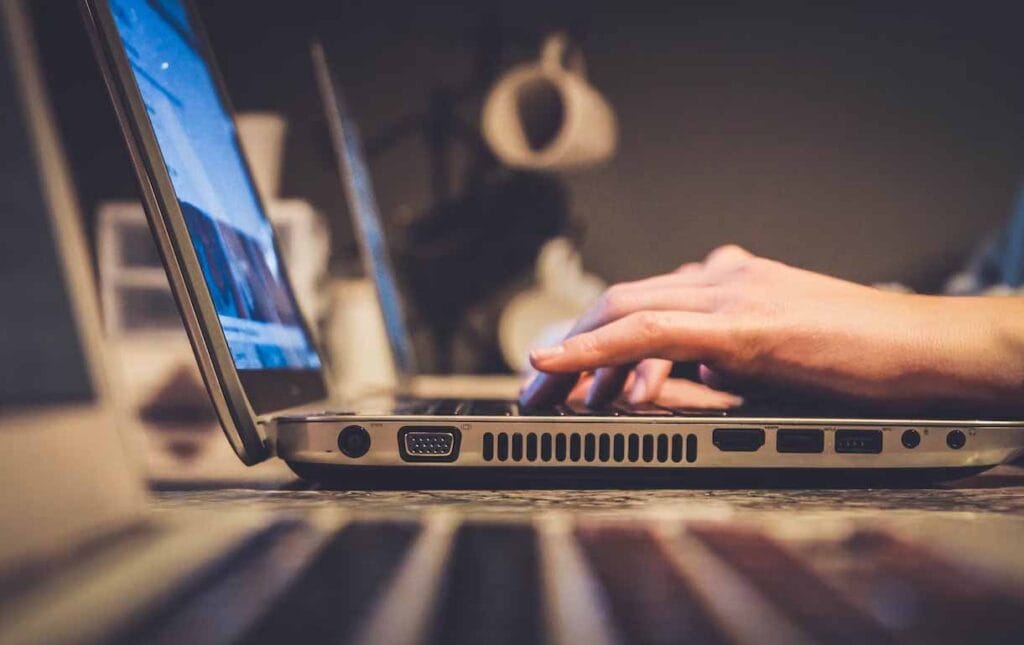 Fingers tapping the keyboard of a laptop.