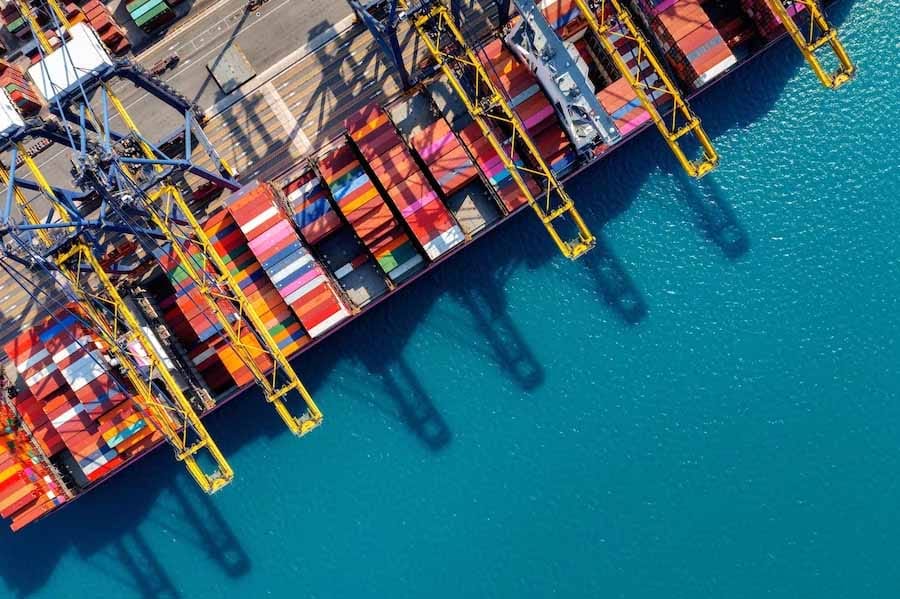 A busy container port terminal with a ship docking and unloading her cargo.