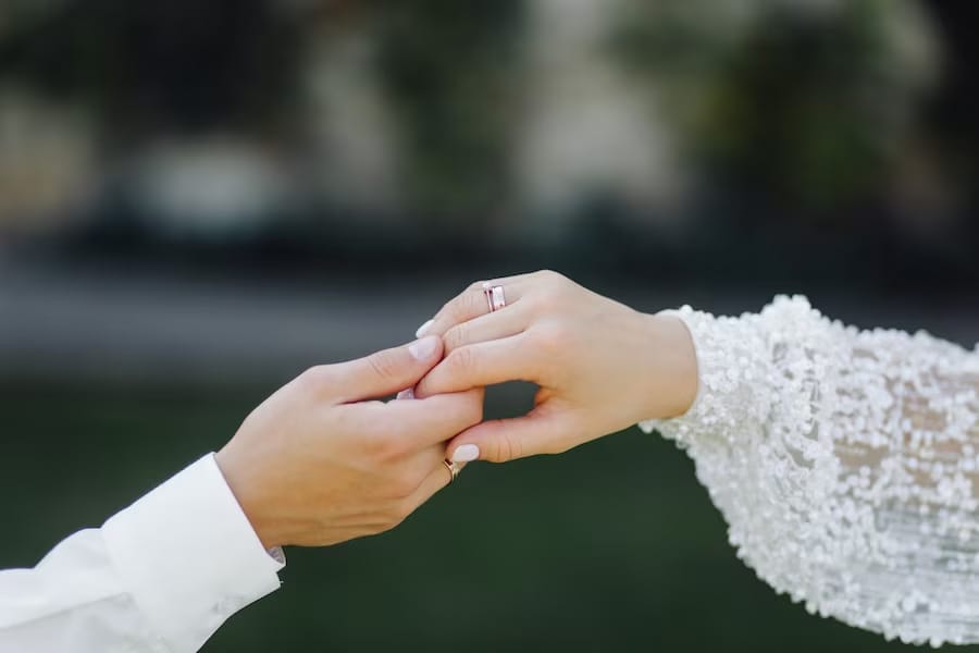 A man holding his wife's left hand showing their wedding ring.