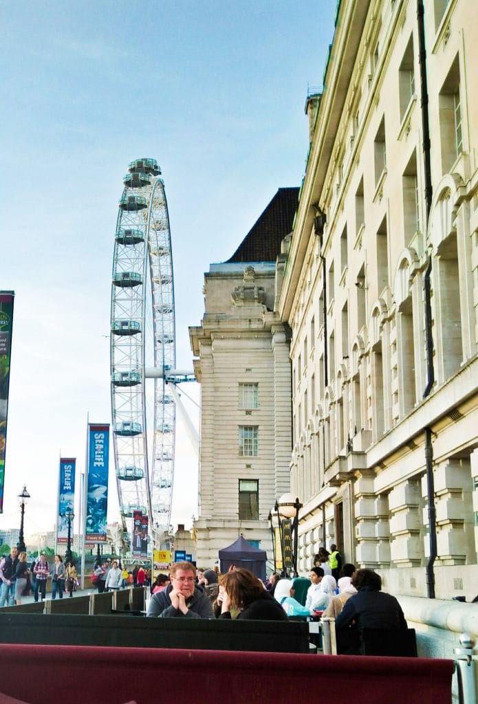 Taking a break near The London Eye and sitting outside the restaurant with fellow tourists to get a view of the Thames and people passing by.