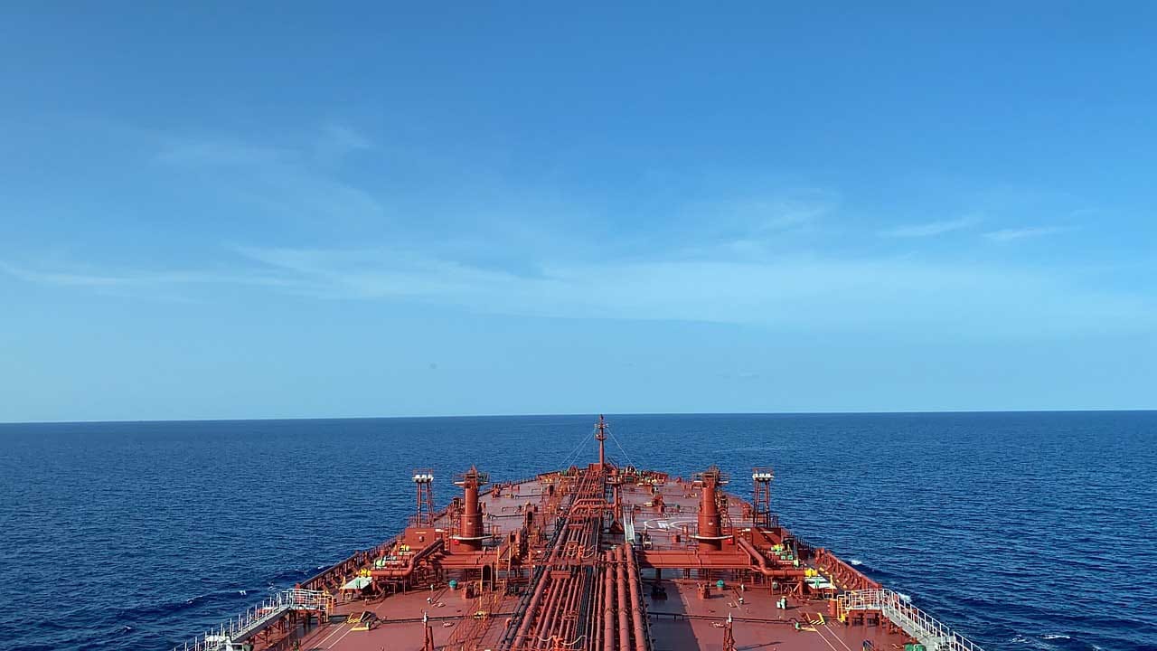 A crude oil tanker sailing in the open ocean as seen from the bridge. Notice the huge expanse of deck area with pipelines and other fittings installed on top.