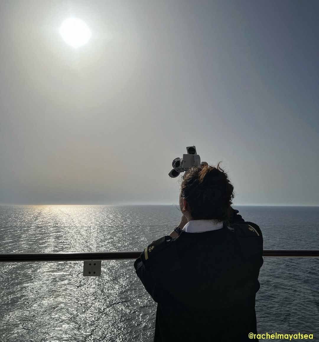 A seawoman taking the altitude of the sun using a sextant to find her position in the middle of the ocean.