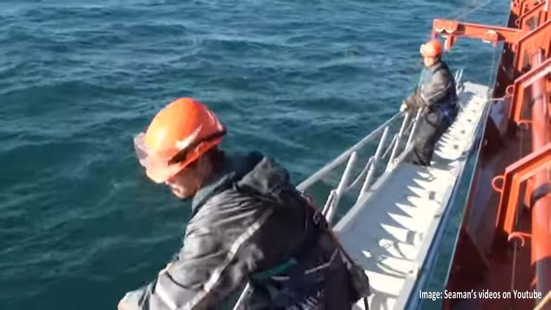 Two deck crew raising the foldable handrails and stanchions together.