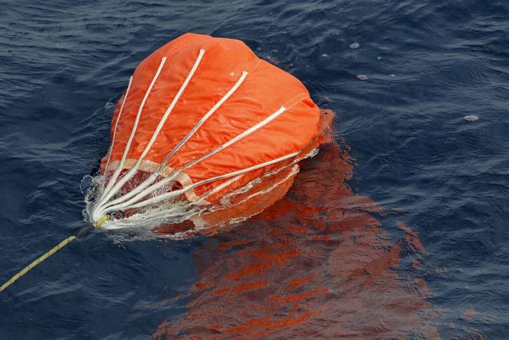 An orange sea anchor or drogue deployed in the sea.