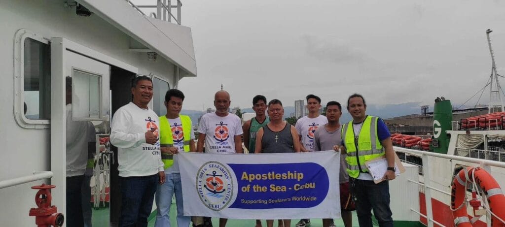 Officers from Stella Maris Seaman's Club visit a ship docked in Cebu and together they take a picture with a banner.