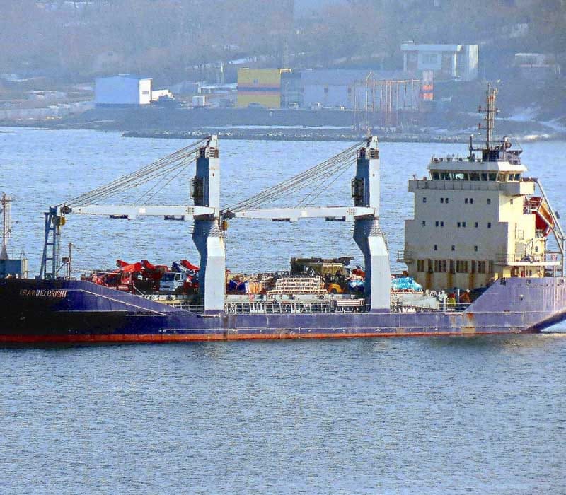 A general cargo vessel carrying different cargoes on deck.