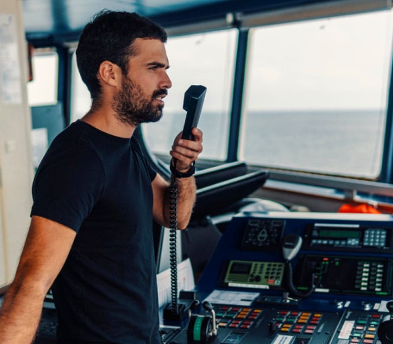 A ship officer communicating with other station using the VHF Radio on the bridge.