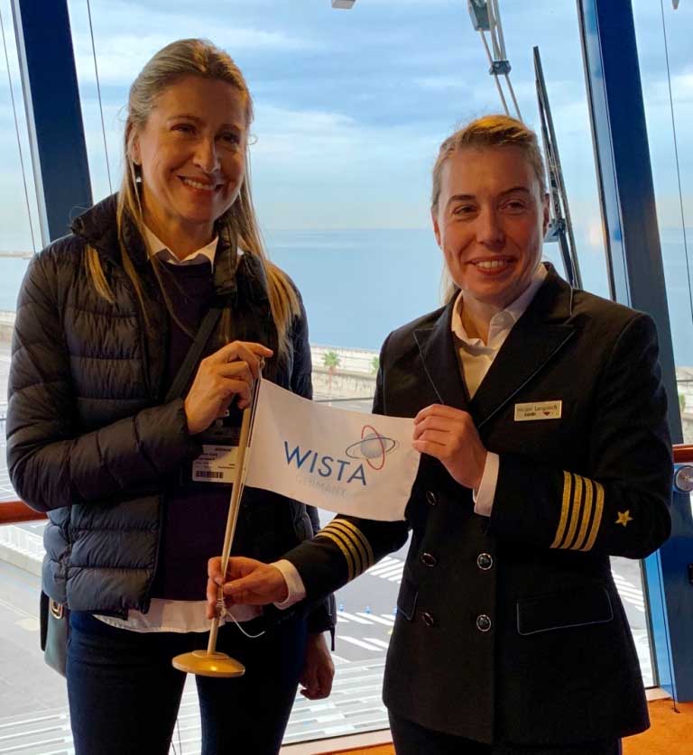 Female Ship Captain Nicole Langosch and a WISTA member holding a small WISTA International flag.